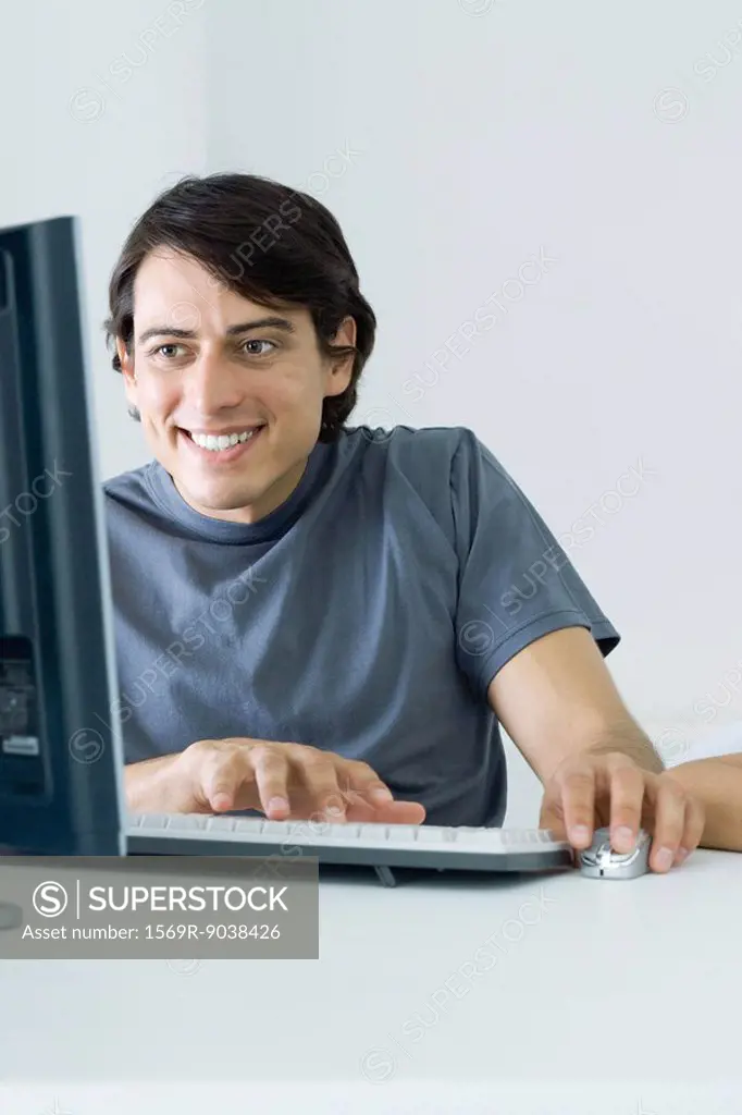 Man using desktop computer, smiling