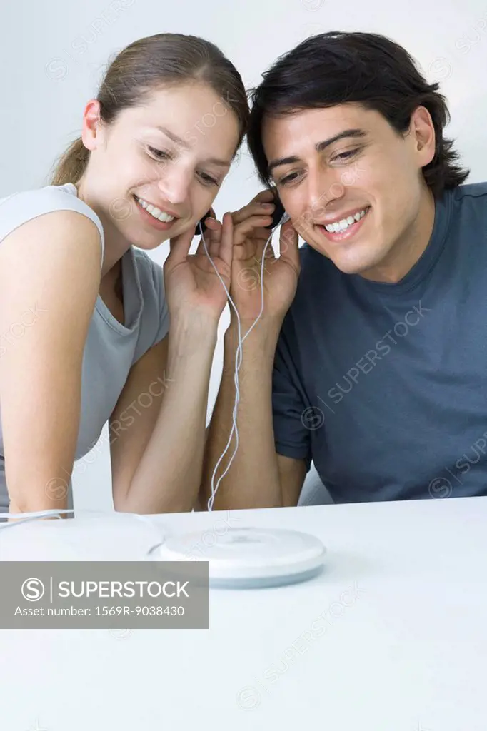 Couple sharing earphones, listening to portable CD player