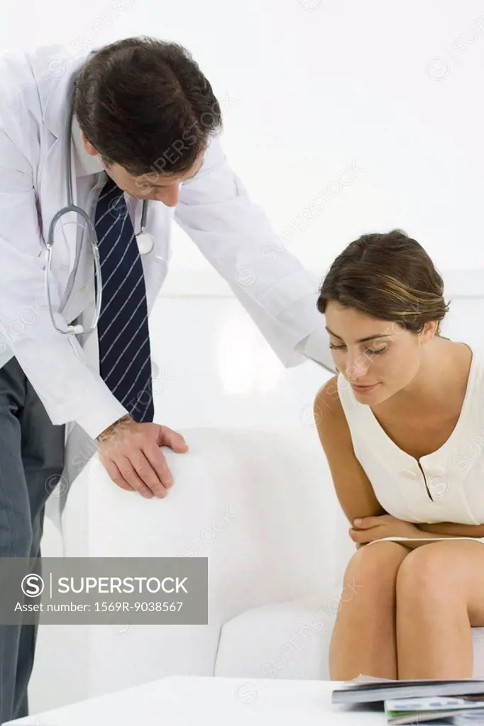 Woman bending over, holding stomach, doctor leaning over to check on her