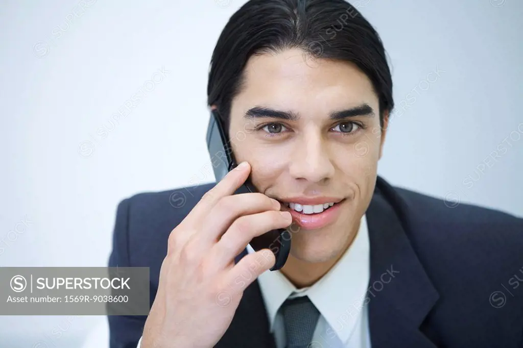 Young professional man holding cell phone, smiling, portrait