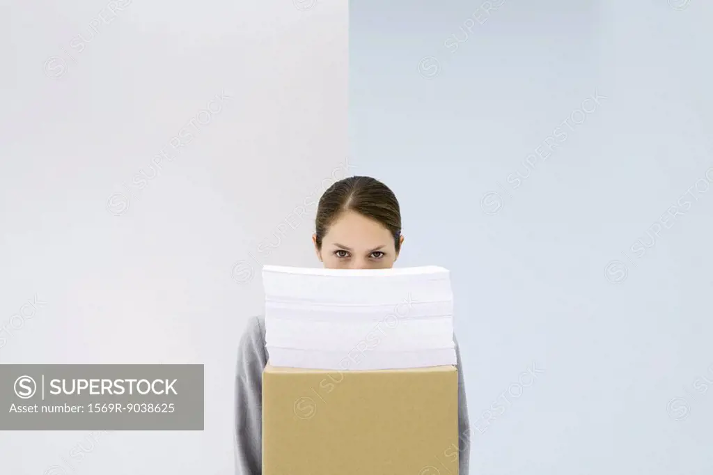 Woman peeking over stack of paper on top of cardboard box