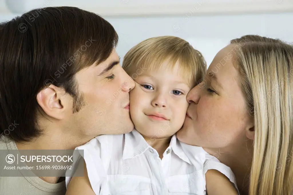 Parents kissing little boy´s cheeks, boy looking at camera