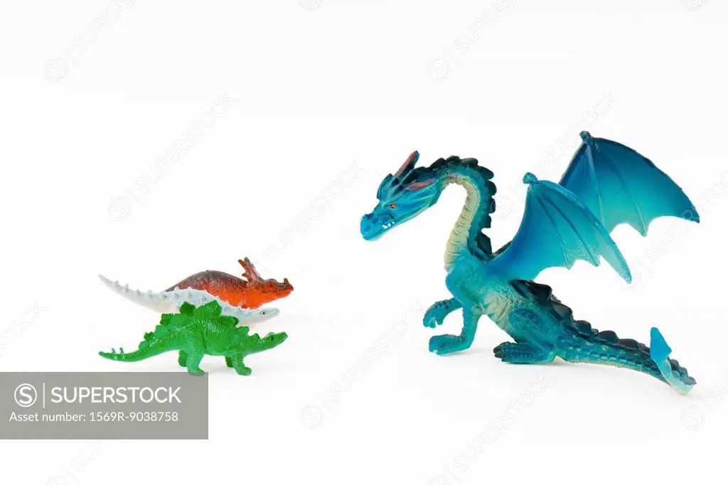 Toy dragon facing three small toy dinosaurs