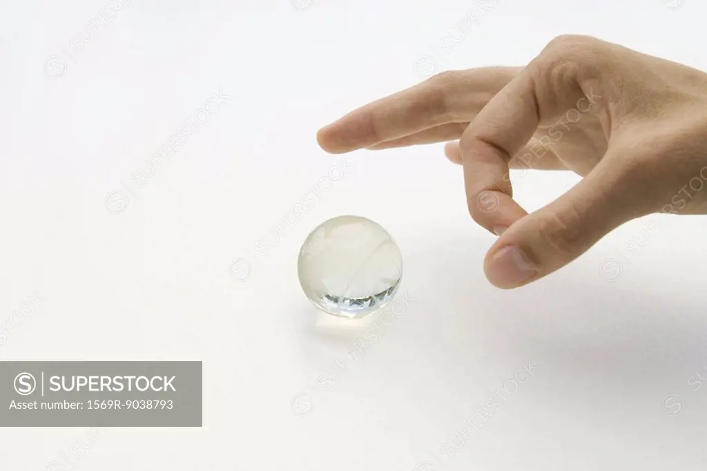 Hand about to flick small glass globe