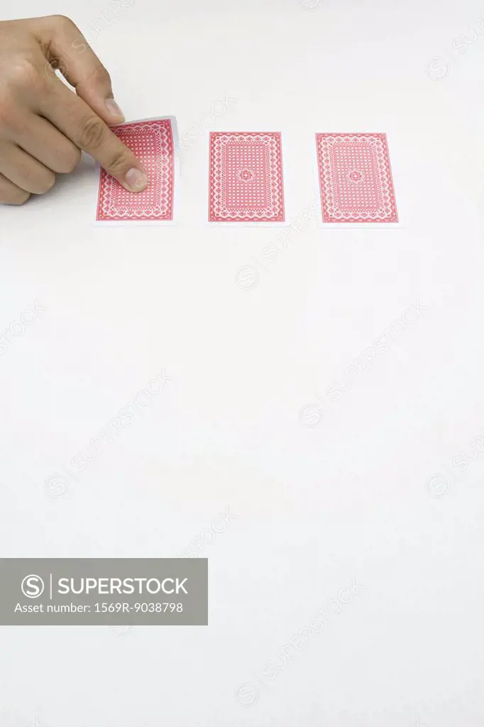 Hand turning over one of three cards