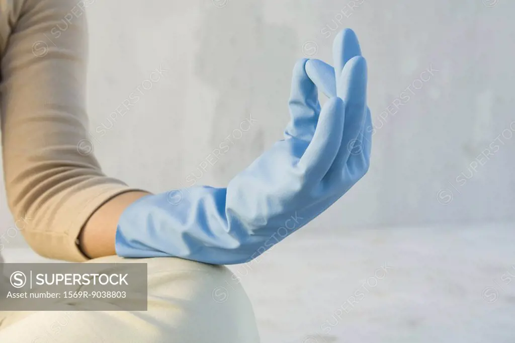 Person meditating with hand in mudra position, wearing rubber glove, cropped view