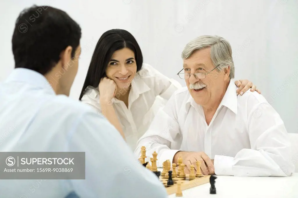 People playing chess, woman sitting with hand on senior man´s shoulder