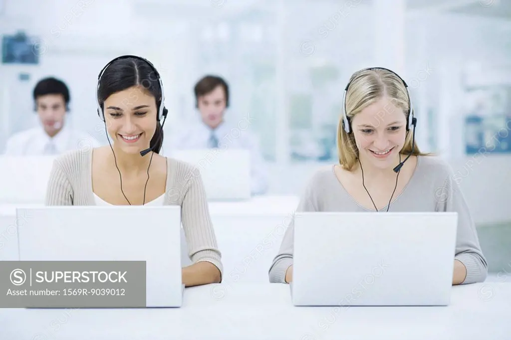 Telemarketers working in call center, smiling