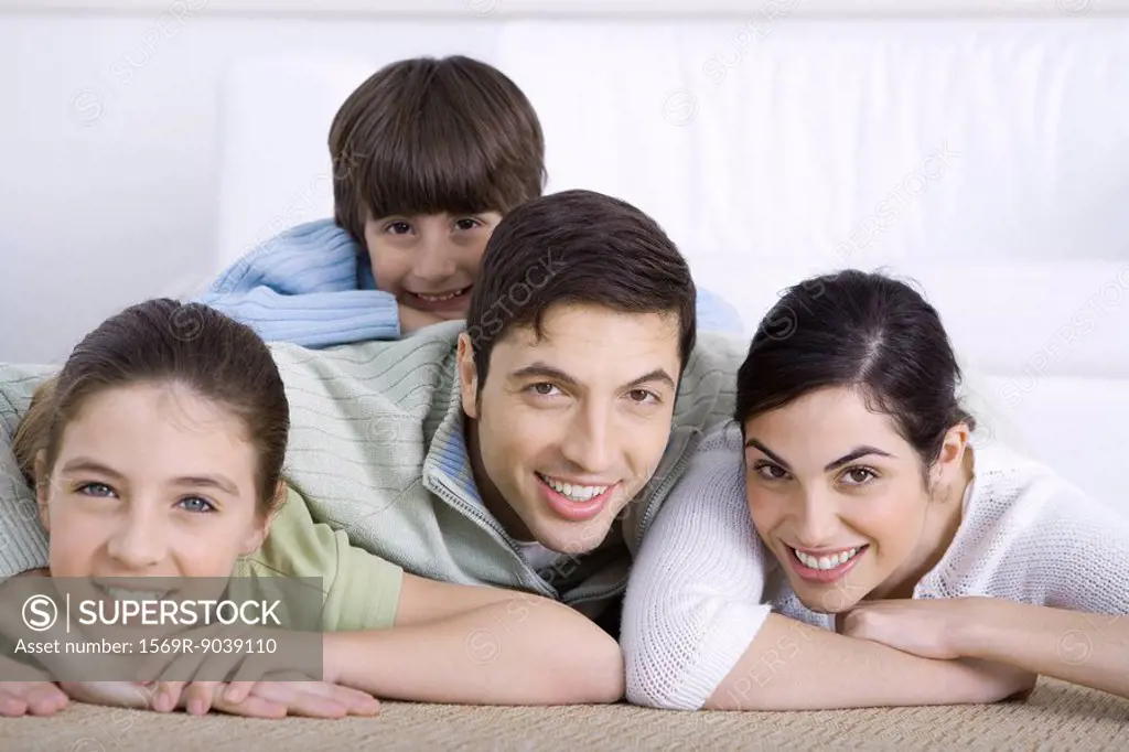 Portrait of smiling family lying together on floor, son lying on his father´s back