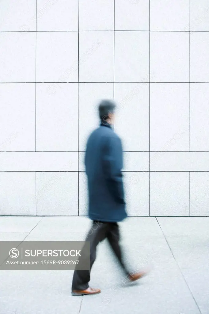 Man walking with hands in pockets down sidewalk