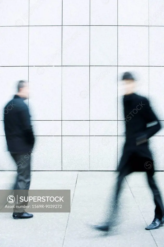 Two men passing one another as they walk along the sidewalk