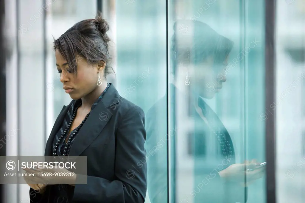 Businesswoman using cell phone, looking down