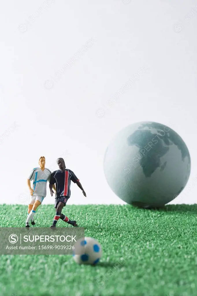 Miniature soccer players chasing soccer ball, globe in background