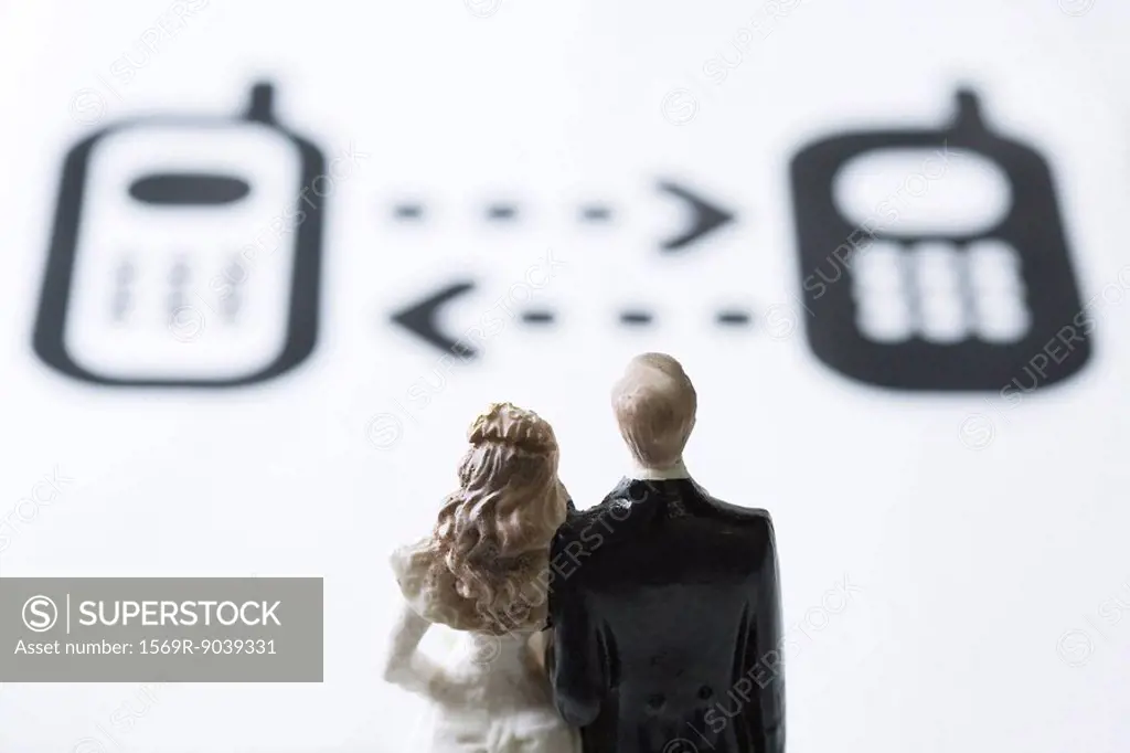 Miniature couple looking at cell phone graphics with arrows between them