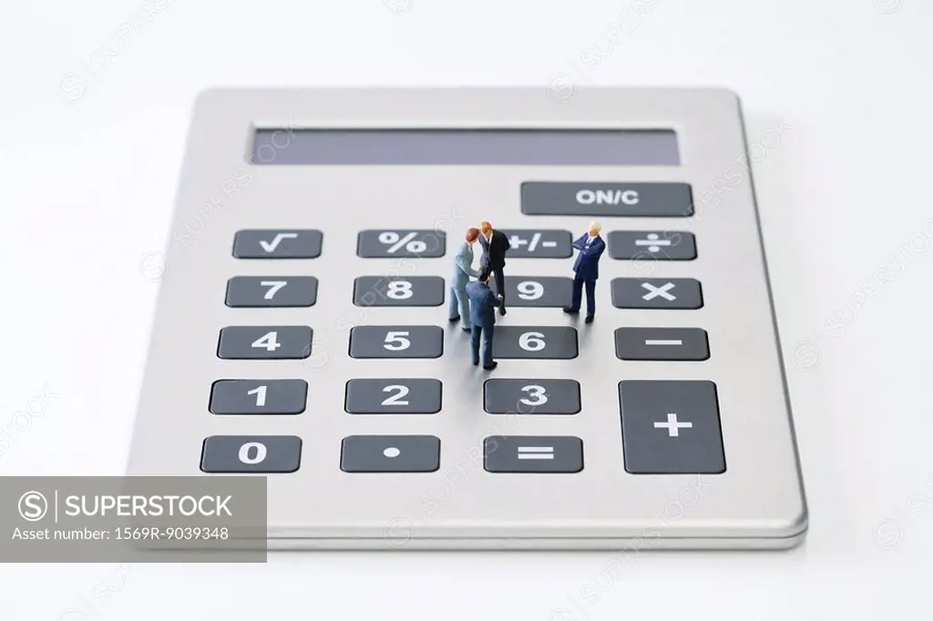 Miniature businessmen standing on calculator