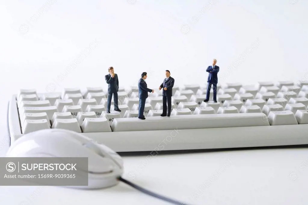 Miniature businessmen standing on computer keyboard