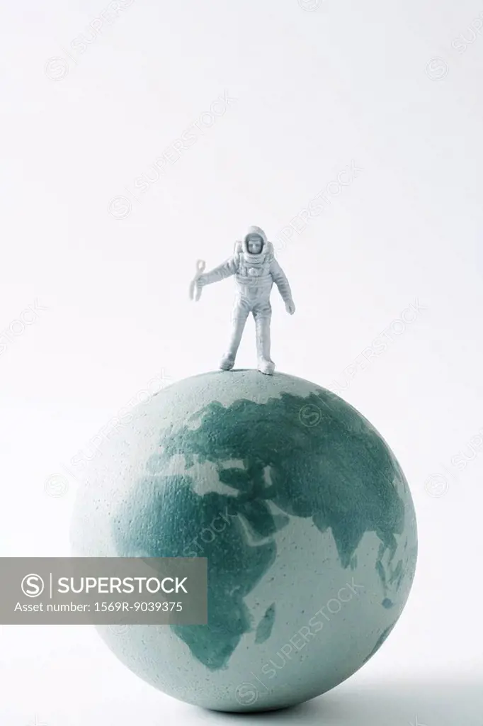 Miniature astronaut standing on top of globe