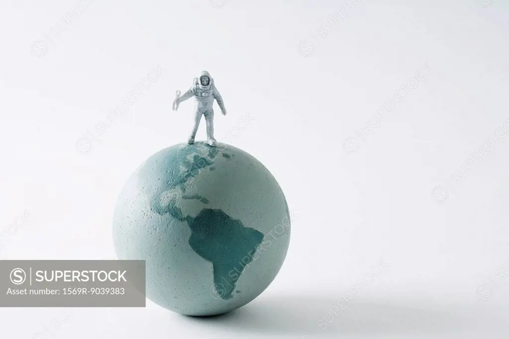 Miniature astronaut standing on top of globe