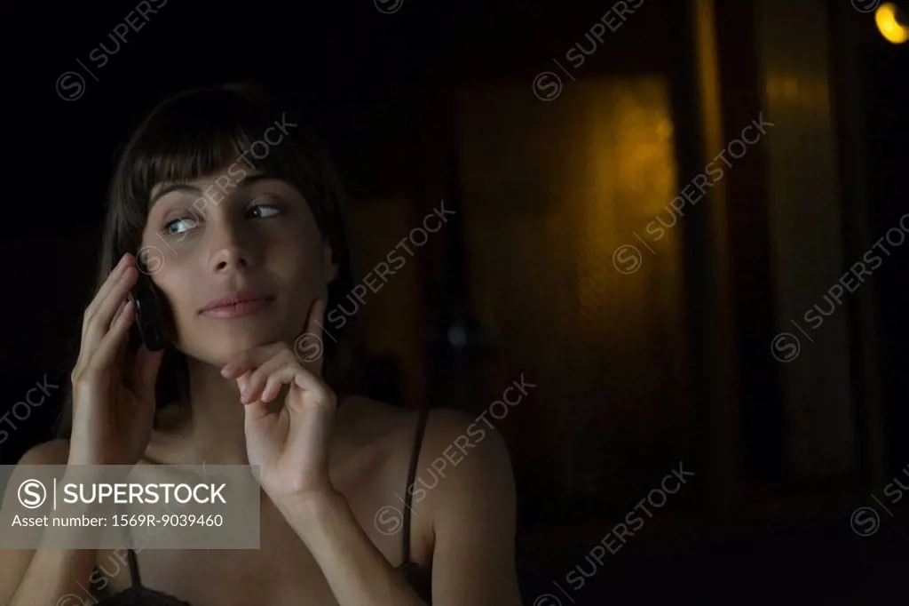 Woman talking on cell phone, hand under chin, looking away