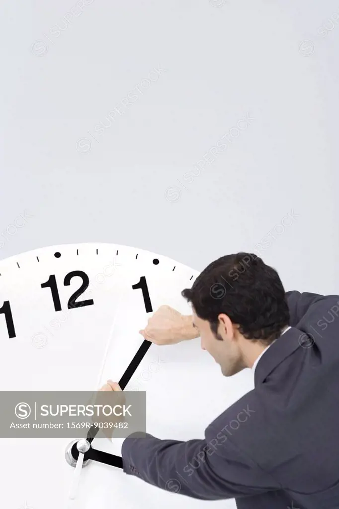 Businessman trying to turn back hands of clock