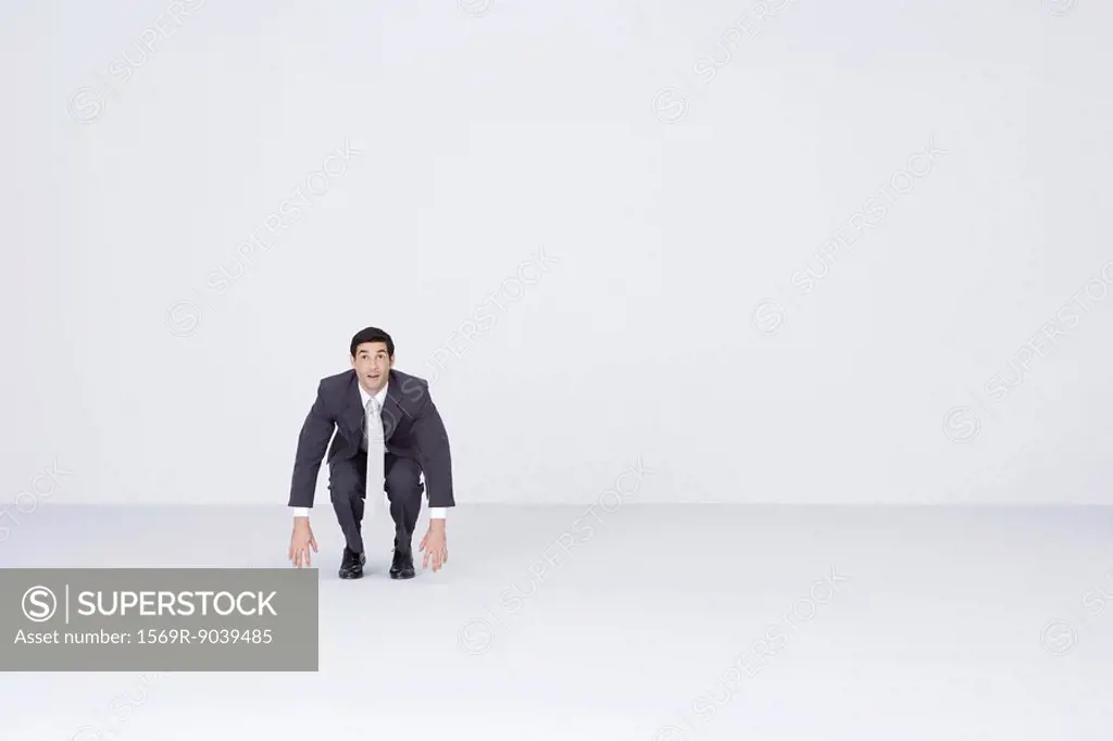 Businessman squatting, dangling arms
