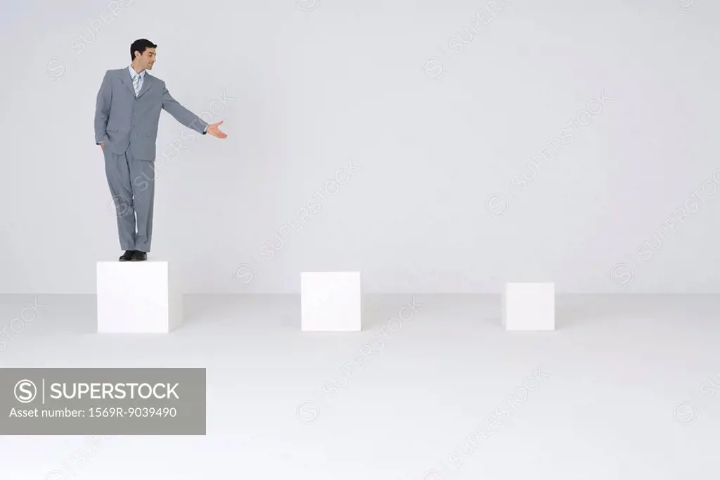 Businessman standing on pedestal, presenting empty pedestals