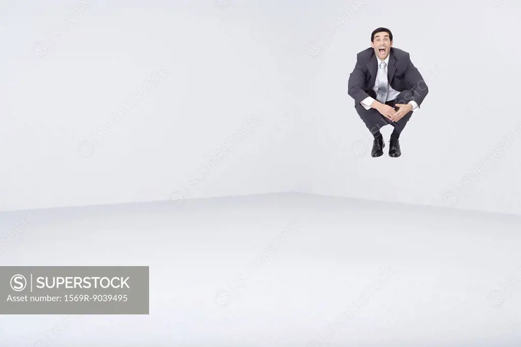 Businessman jumping in midair, shouting at camera