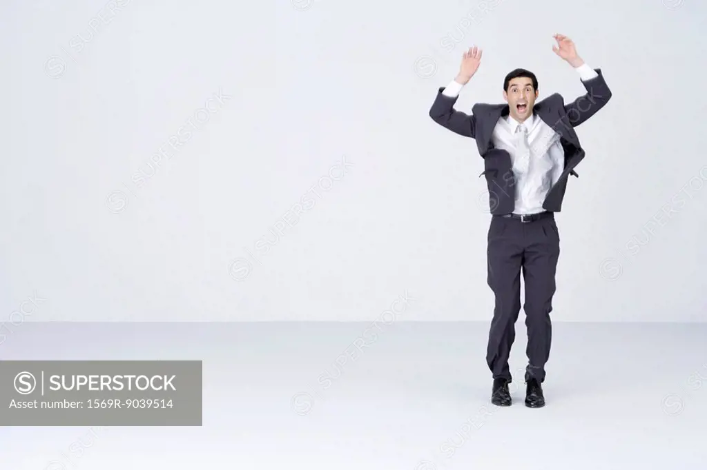 Businessman standing with arms up, mouth and eyes wide open