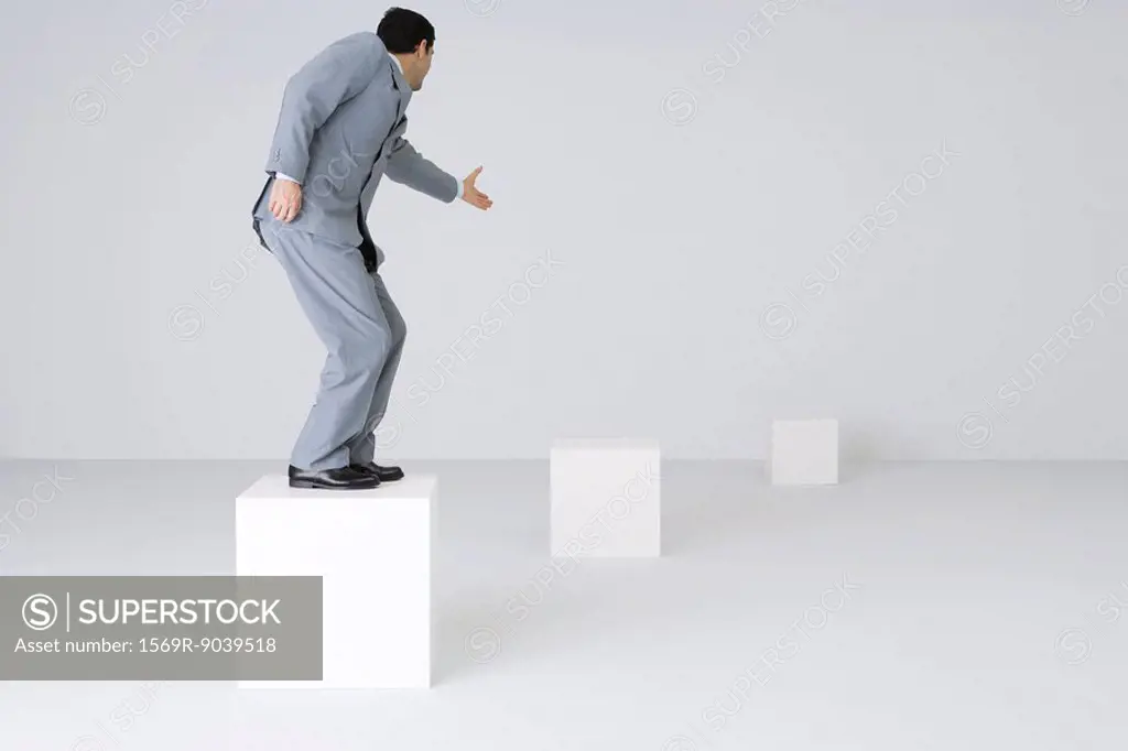 Businessman standing on block, reaching out hand