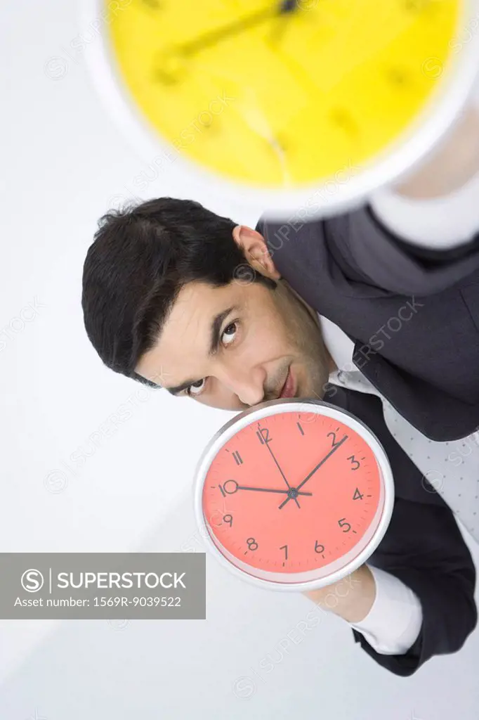 Businessman holding up clocks, looking at camera
