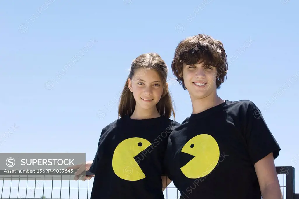Young couple wearing tee-shirts printed with graphic characters, smiling at camera