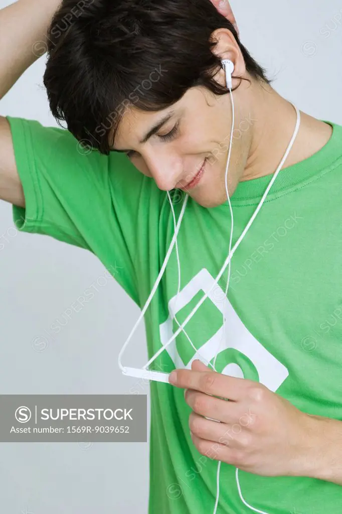Young man listening to MP3 player, smiling, looking down