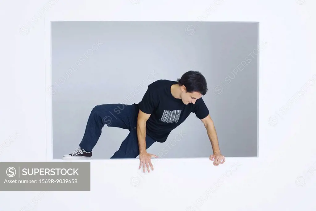 Man climbing over wall, wearing tee-shirt with bar code printed on it