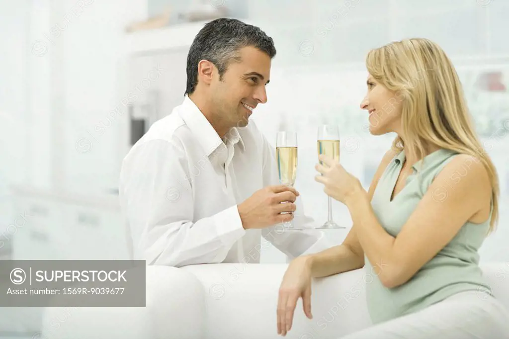 Couple holding champagne glasses, smiling at each other