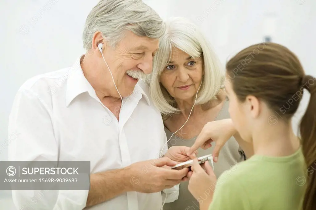 Young girl showing grandparents how to use MP3 player