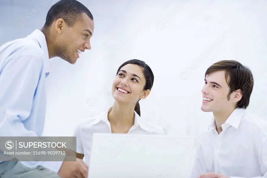 Young professionals smiling at each other, sitting near laptop