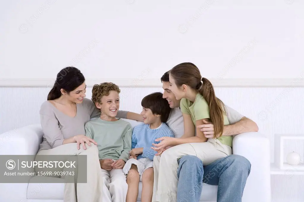 Family with three children sitting together on sofa, talking