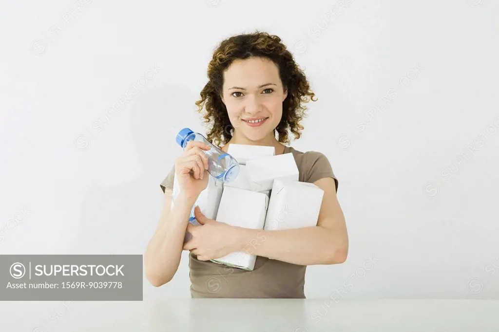 Woman holding an armful of milk cartons and baby bottle, smiling at camera