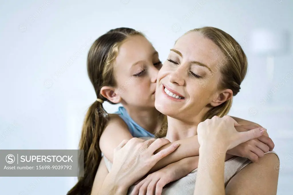 Mother and daughter embracing, girl kissing woman´s cheek