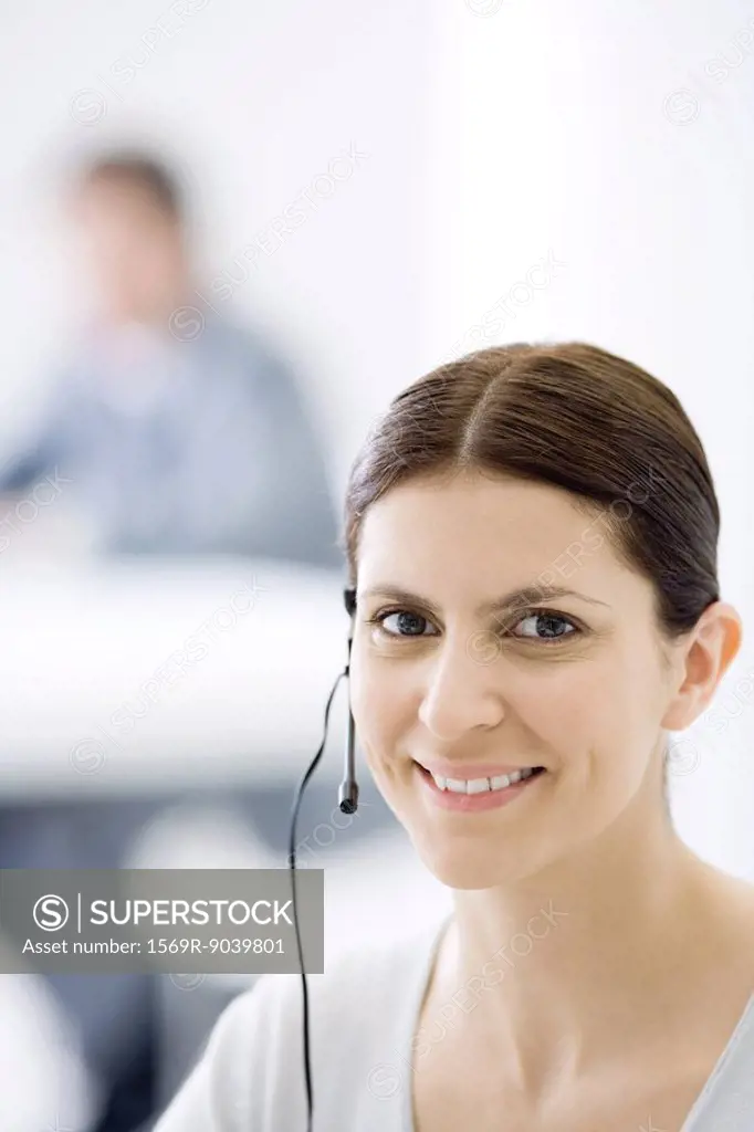 Woman wearing headset, smiling at camera, portrait