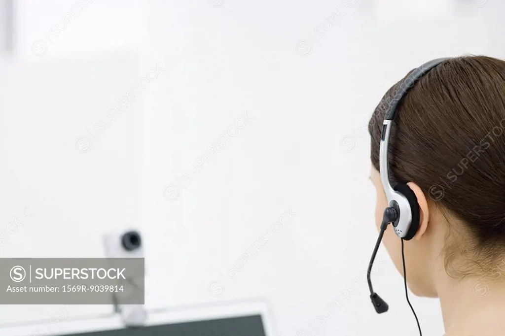 Woman wearing headset, looking at webcam, rear view