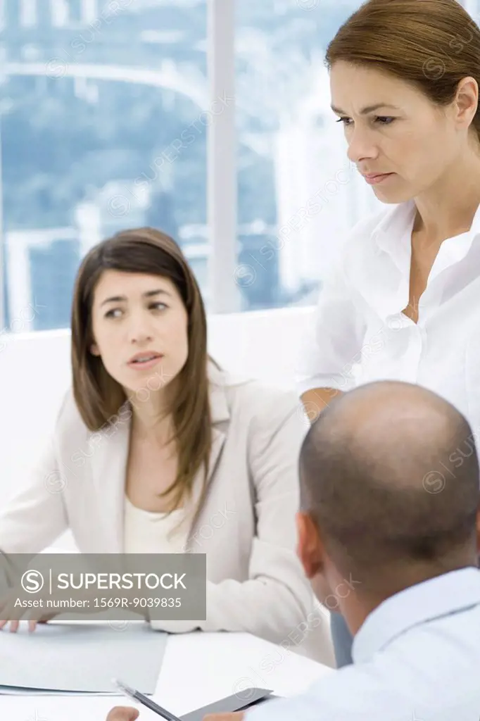 Professionals having a meeting at desk, focus on standing woman
