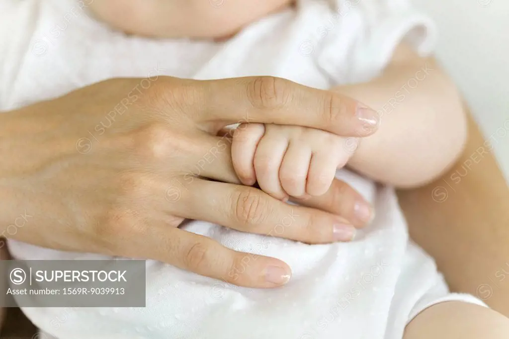 Baby´s hand holding adult´s finger, close-up