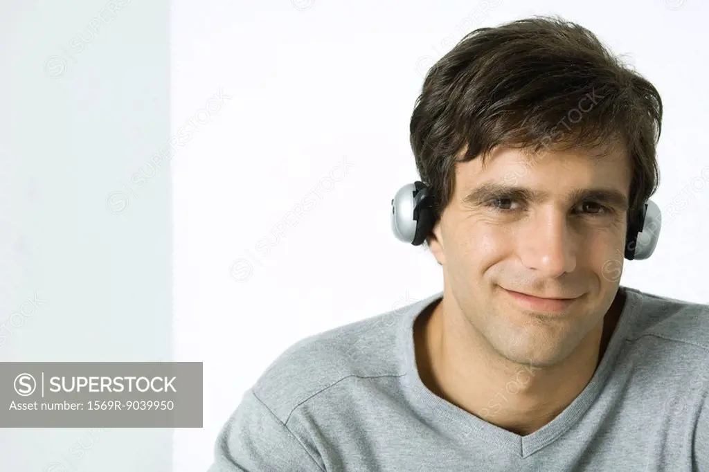 Man listening to headphones, smiling at camera