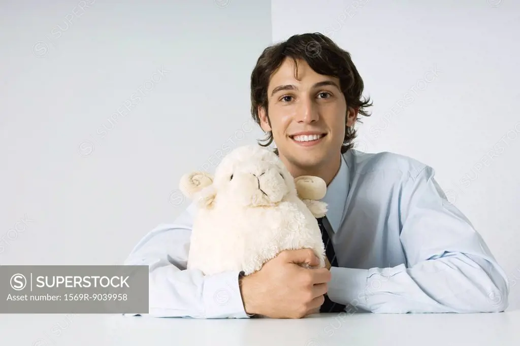 Young man hugging stuffed toy, smiling at camera