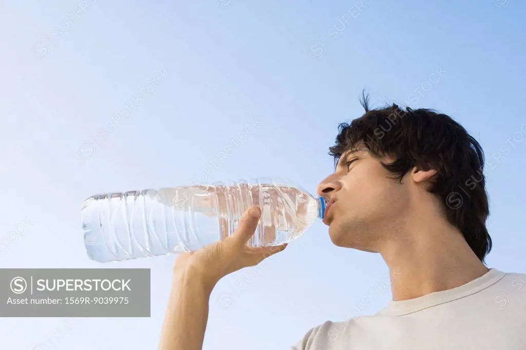 Man drinking large bottle of water, low angle view