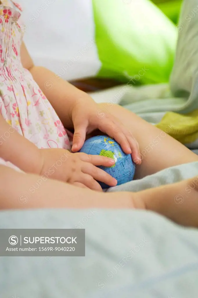 Infant holding toy globe, cropped