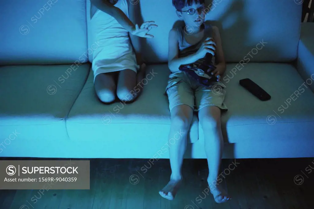 Boy playing video game, sister reaching for joystick