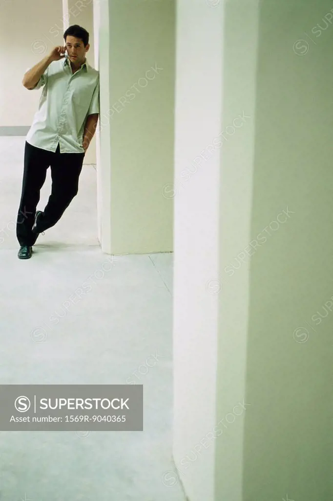 Man leaning in doorway, talking on cell phone