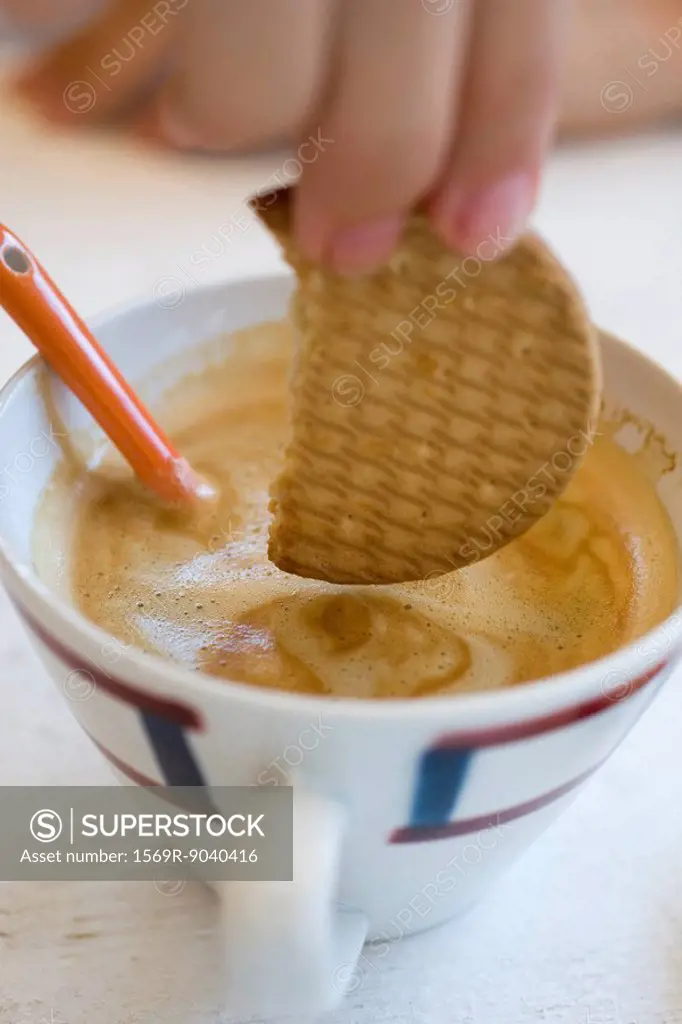 Dipping wafer in cup of cappuccino